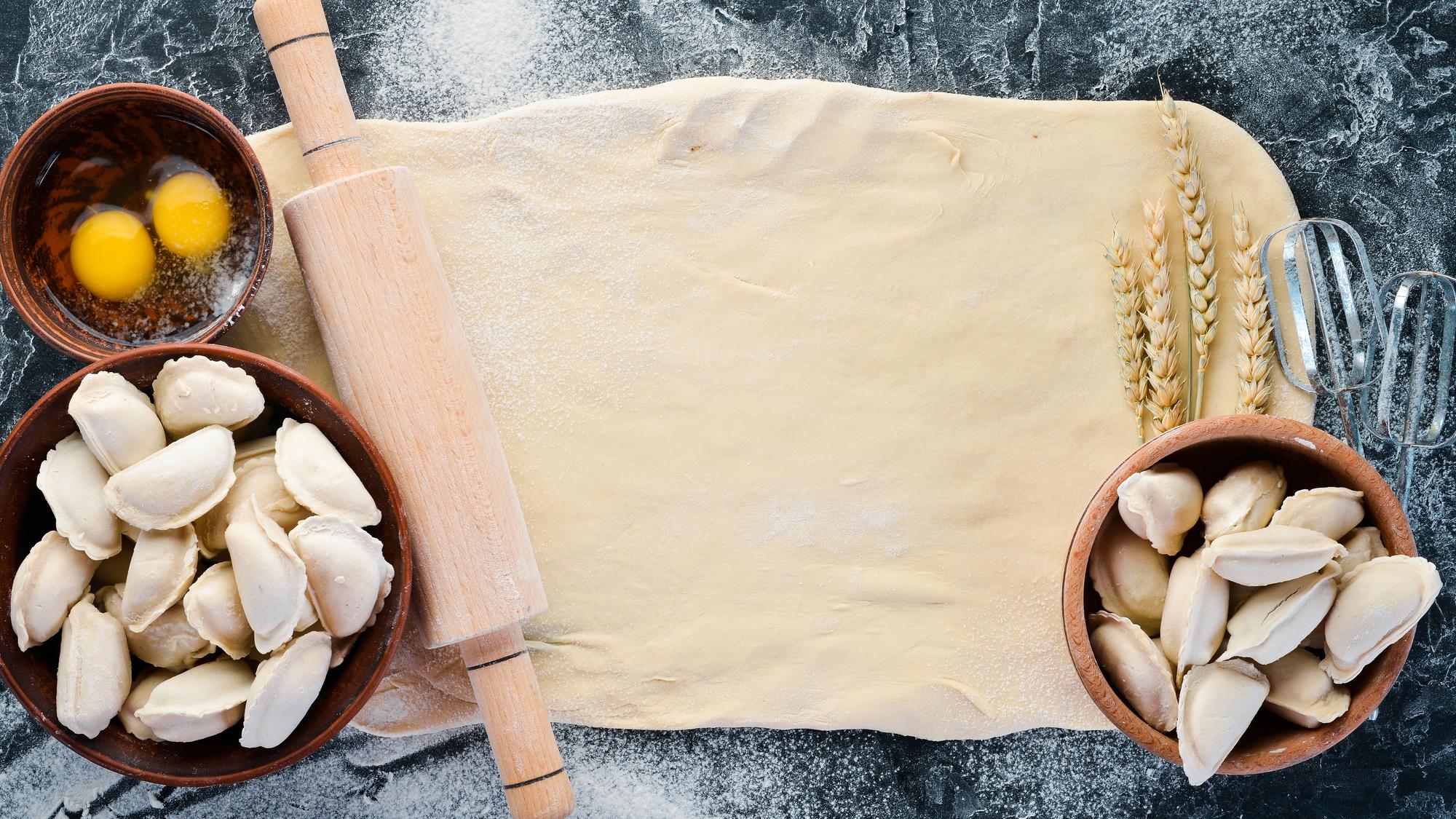 fresh pasta being rolled on wooden board